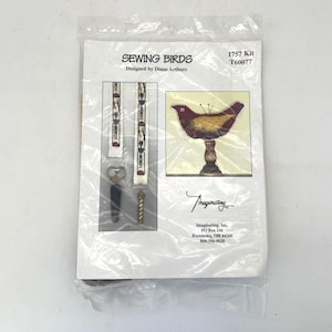 May include: A sewing kit titled "SEWING BIRDS" by Diane Arthurs, packaged in a clear plastic bag. The kit includes an image of a bird-shaped pincushion and decorative elements. The text "1757 Kit T60077" is visible.