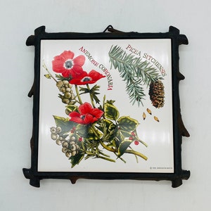 May include: Square ceramic tile featuring a botanical illustration of red anemone flowers, pine needles, and a pine cone. The tile is set in a dark brown, rustic, wooden frame. Text on the tile reads "ANEMONE CORONARIA" and "PICEA SITCHENSIS".