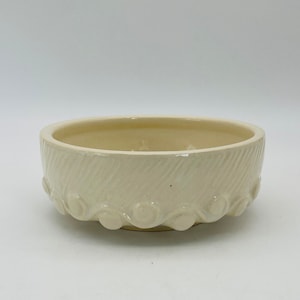 May include: A white ceramic bowl with a wavy, textured rim and a diagonal pattern on the side.