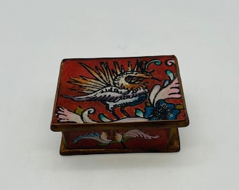 May include: A small, red wooden box with a hinged lid. The box is decorated with a colorful painted design of a bird with a long tail and flowers.