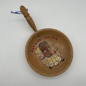 May include: A wooden bowl with a handle, painted with a cartoon potato wearing a dress and the words "Potato Chips".