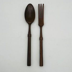 May include: A set of wooden utensils, a spoon and a fork, both with dark brown handles.