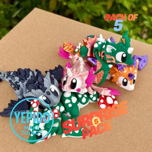 May include: A selection of five dragon figurines in a variety of colours. The dragons feature details such as mushrooms and polka dots, with shades of green, pink, orange, and grey. Text reads "PACK OF 5" and "SURPRISE PACK".