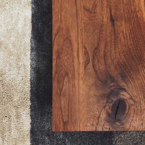 May include: Close-up of a dark brown wooden surface with a knot in the grain. The wood is smooth and polished.