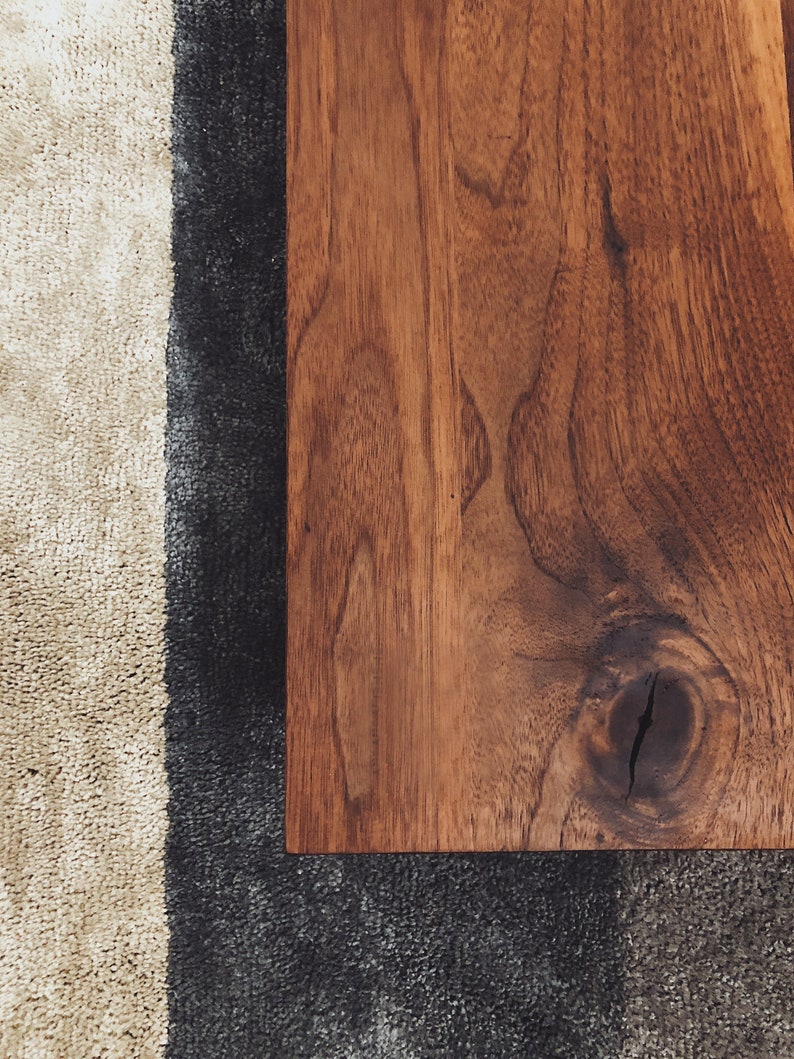 May include: Close-up of a dark brown wooden surface with a knot in the grain. The wood is smooth and polished.
