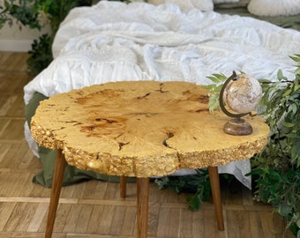 May include: A wooden table with a live edge top and four legs. The table is made of light wood with a natural finish. A small globe sits on the table.
