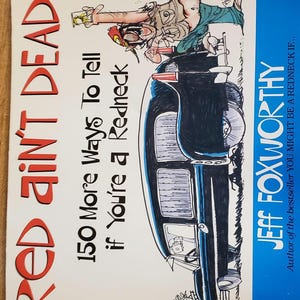 May include: A book cover with the title "RED AIN'T DEAD" in red letters. The book is titled "150 More Ways To Tell if You're a Redneck" by Jeff Foxworthy. The cover features a cartoon of a person and a car.