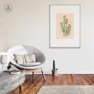 Printable wall art of green saguaro cactus on tan background. Shown in living room.