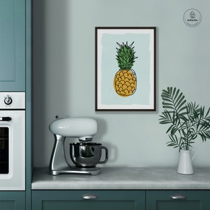 Kitchen wall art of pineapple with gold base and green leaves on blue background. Shown in kitchen.