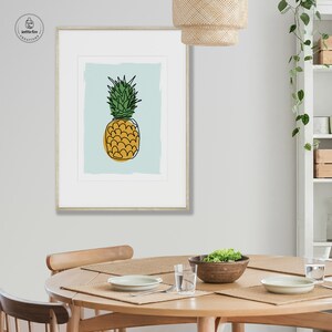 Kitchen wall art of pineapple with gold base and green leaves on blue background. Shown in kitchen.
