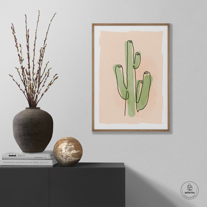 Printable wall art of green saguaro cactus on tan background. Shown in living room.