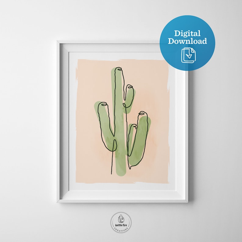 Printable wall art of green saguaro cactus on tan background. Shown in frame.