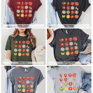 May include: Five different color t-shirts with a graphic print of a variety of sliced vegetables and fruits. The colors of the shirts are heather cardinal, black heather, military green, dark grey heather, and deep heather.