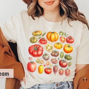 May include: A white t-shirt with a colorful illustration of various tomatoes, including whole tomatoes, tomato slices, and green peppers. The text "Soft Cream" is visible in the lower left corner of the image.