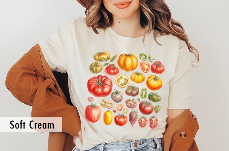 May include: A white t-shirt with a colorful illustration of various tomatoes, including whole tomatoes, tomato slices, and green peppers. The text "Soft Cream" is visible in the lower left corner of the image.