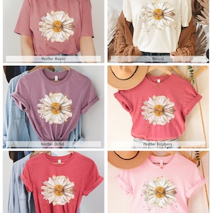 Pode incluir: Uma cole&ccedil;&atilde;o de seis t-shirts com um design de margarida em aquarela. As camisas est&atilde;o dispon&iacute;veis em Heather Mauve, Natural, Heather Orchid, Heather Raspberry, Heather Red e Rosa.