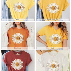 Pode incluir: Seis t-shirts de diferentes cores com uma estampa de margarida em aquarela. As cores s&atilde;o amarelo, amarelo dourado mesclado, laranja queimado, dourado, argila mesclada e cinza.