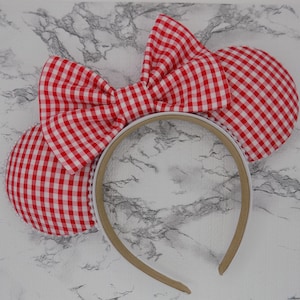 May include: Red and white gingham Minnie Mouse ears headband with a large bow on top.