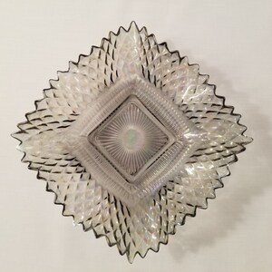 May include: A square iridescent glass dish with a diamond pattern and a smaller square in the center. The dish has a scalloped edge.