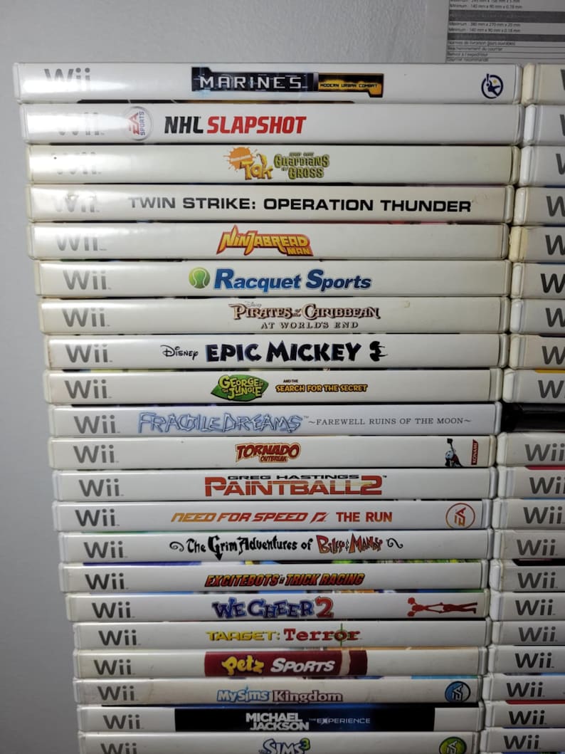 May include: A stack of 20 white Nintendo Wii game cases with colorful game covers. The games include "NHL Slapshot", "Twin Strike: Operation Thunder", "Racquet Sports", "Pirates of the Caribbean", "Epic Mickey", "Fragile Dreams", "Tornado Outbreak", "Paintball 2", "Need for Speed: The Run", "The Grim Adventures of Billy & Mandy", "Excitebots: Trick Racing", "We Cheer 2", "Target: Terror", "Petz Sports", "MySims Kingdom", "Michael Jackson: The Experience", and "Sims 3".