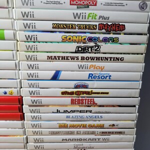 May include: A stack of 20 video game cases for the Nintendo Wii console. The games include titles like Just Dance 2017, Monster Trucks Mayhem, Sonic Colors, Dirt 2, and more.