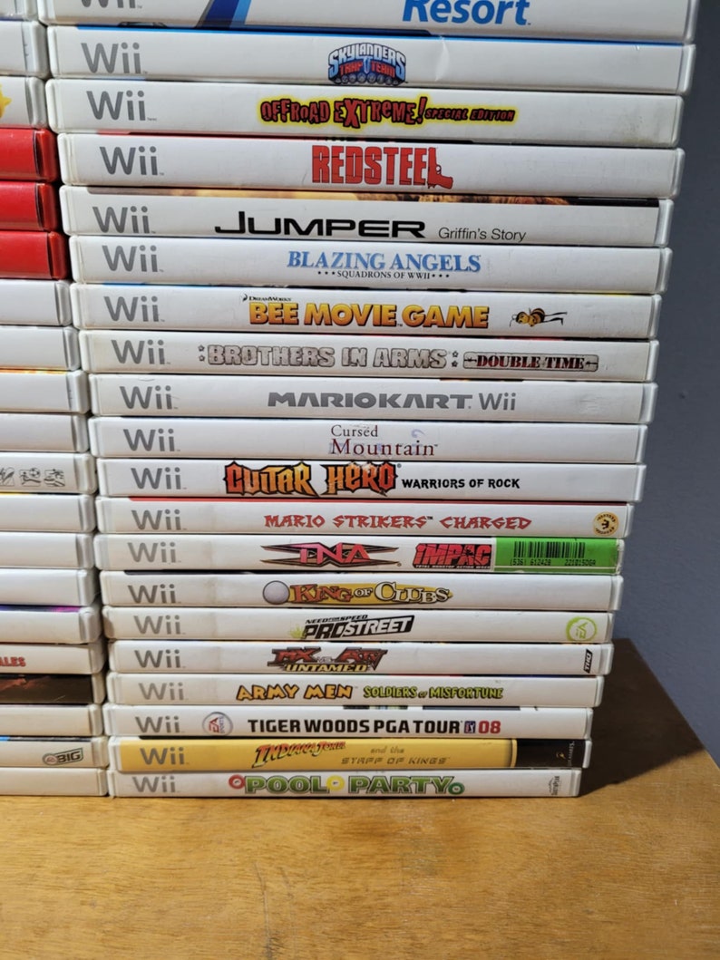 May include: A stack of 16 Nintendo Wii video game cartridges, including titles like "Redsteel", "Blazing Angels", "Bee Movie Game", "Mario Kart Wii", "Guitar Hero Warriors of Rock", "Mario Strikers Charged", "Army Men Soldiers of Misfortune", and "Tiger Woods PGA Tour 08".