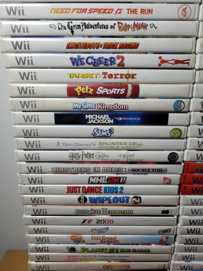 May include: A stack of 20 Nintendo Wii video game cartridges. The games include titles like Need for Speed, The Grim Adventures of Billy & Mandy, Excitebots: Trick Racing, We Cheer 2, Target: Terror, Petz Sports, MySims Kingdom, Michael Jackson: The Experience, The Sims 3, Splinter Cell: Double Agent, Harry Potter and the Order of the Phoenix, Brothers in Arms: Double Time, NHL 2K11, Just Dance Kids 2, Wipeout, Guitar Hero III: Legends of Rock, F1 2009, Dora's Crystal Kingdom, Planet 51: The Game, Where's Waldo? The Fantastic Journey, and Real Heroes: Firefighter.