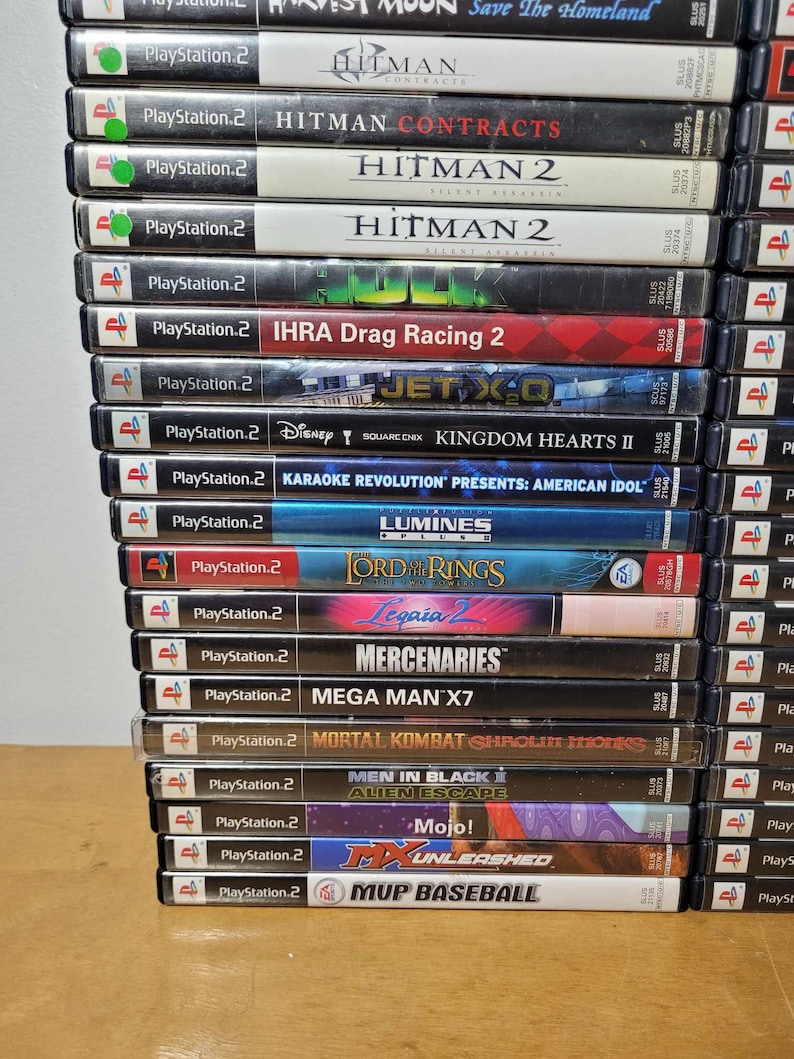 May include: A stack of PlayStation 2 video game cases, including titles like Hitman Contracts, Kingdom Hearts II, Lord of the Rings, and Mega Man X7.