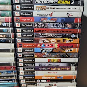 May include: A stack of PlayStation 2 video game cases, including titles like Motocross Mania 3, MX World Tour, Need for Speed Underground, and NHL 2003.