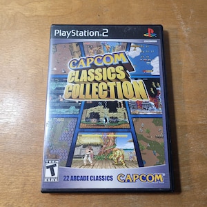 May include: A PlayStation 2 game case for Capcom Classics Collection. The cover displays a collage of colourful screenshots from arcade games. The title is in yellow and blue, with the ESRB rating and "22 Arcade Classics" text.