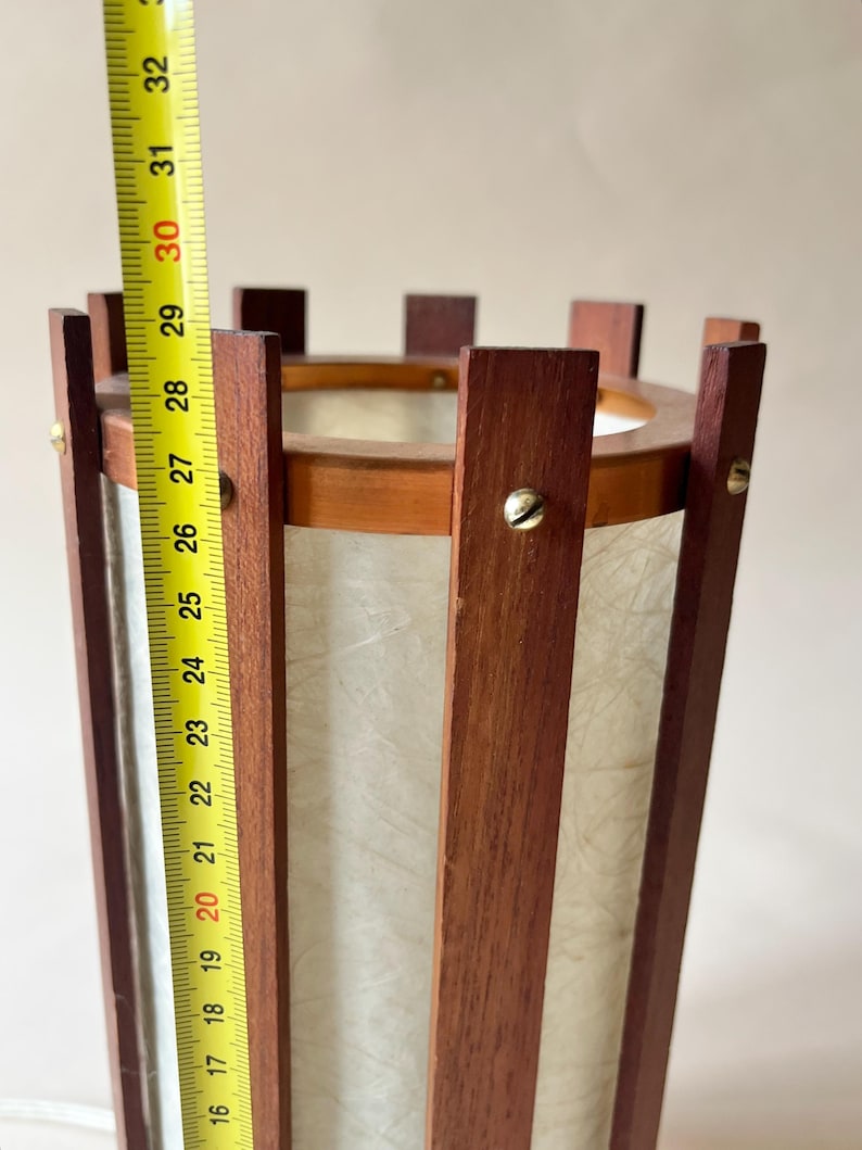 May include: A vintage wooden lamp with a cylindrical shape. The lamp is approximately 30 inches tall, featuring vertical wooden slats and a paper-like shade. The top and bottom are framed with wood, and the lamp has a warm, inviting aesthetic.