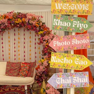Puede incluir: Cinco flechas direccionales de colores con patrones florales y texto blanco. Las flechas indican "Welcome", "Khao Piyo", "Photo Shoto", "Nacho Gao" y "Chai Shai".