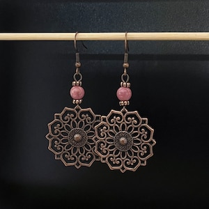 May include: A pair of dangle earrings with a copper filigree design and pink stone beads.