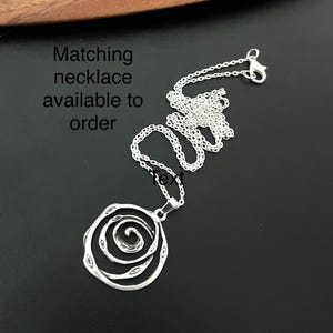 May include: Silver necklace with a spiral design pendant. Matching necklace available to order.
