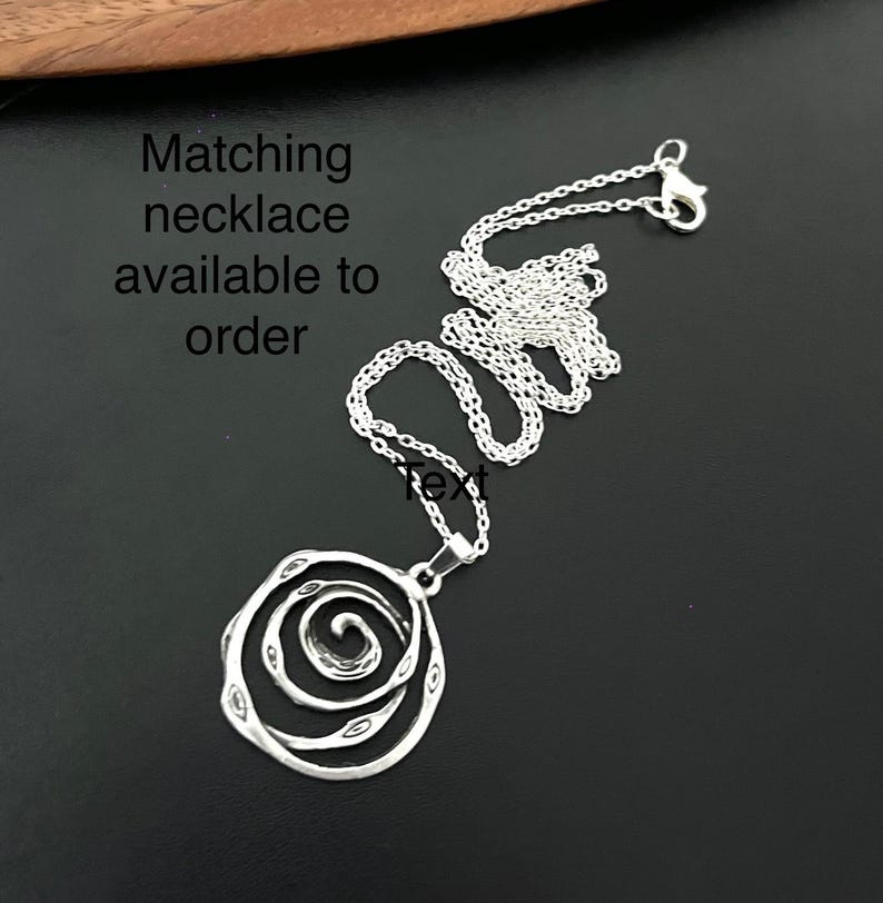 May include: Silver necklace with a spiral design pendant. Matching necklace available to order.