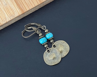 Puede incluir: Un par de pendientes de bronce con cuentas turquesa y dijes en forma de moneda.