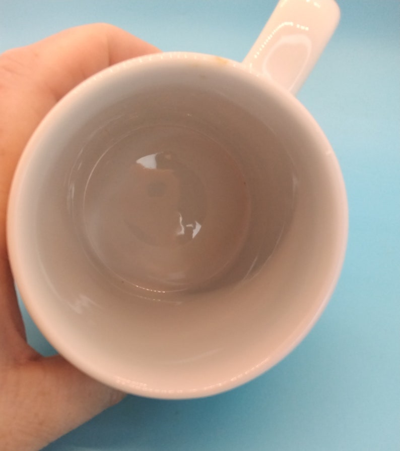 May include: White ceramic mug with a handle. The mug is empty and clean.