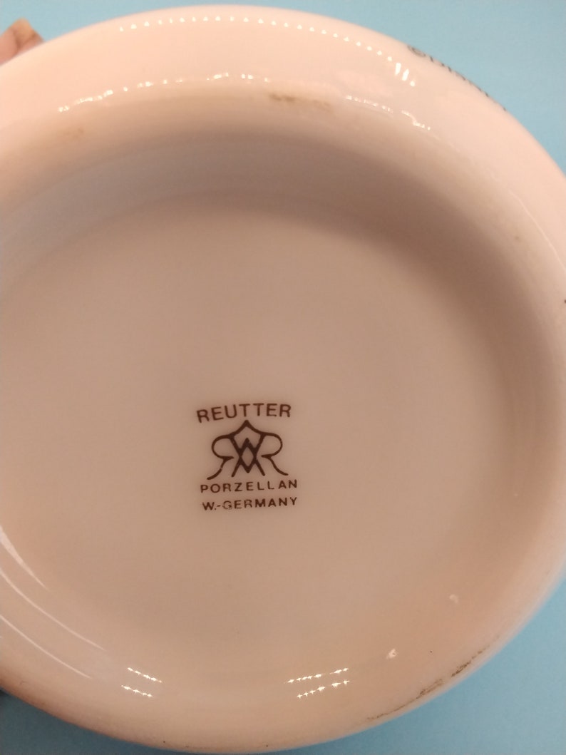 May include: Close-up of the bottom of a white porcelain dish with a brown logo that reads "Reutter Porzellan W-Germany".