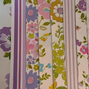 May include: A collection of vertical wallpaper strips featuring various floral patterns in shades of pink, purple, orange, yellow, and green, alongside striped designs, arranged side-by-side to display a variety of colorful botanical motifs.