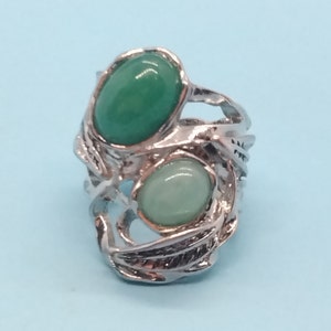 May include: A silver ring with a leafy design and two oval-shaped green gemstones.