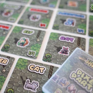 Peut inclure: Gros plan sur un jeu appelé "Pixel Party" de Tiny Token. Le jeu comprend une variété de personnages pixélisés, dont un chat, un rat, un soldat et un elfe. Le jeu se joue sur une grille de cases, et les joueurs déplacent leurs personnages sur le plateau.