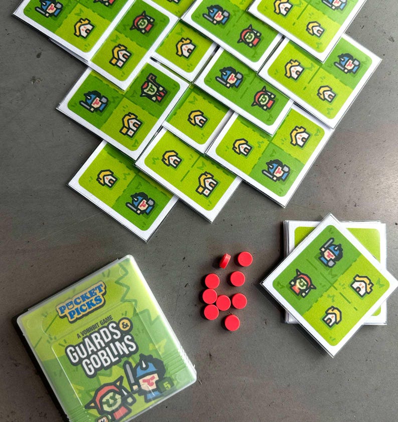 May include: A green and yellow board game called "Pocket Picks: Guards & Goblins". The game includes a variety of cards with illustrations of guards and goblins. There are also red game pieces.