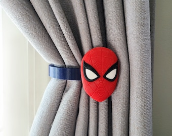 Può includere: Un fermacortina in plastica rosso e nero con il viso di Spider-Man. Il fermacortina ha un cinturino blu.