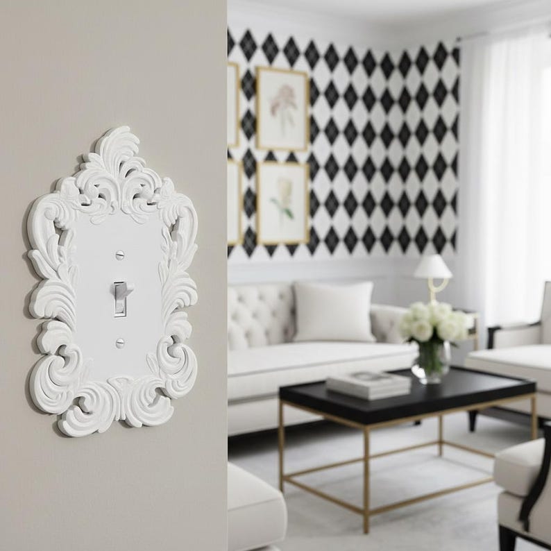 May include: A white, ornate light switch cover with a decorative, scroll-like design. The cover is mounted on a light gray wall. The switch is in the on position. The background shows a living room with a black and white diamond pattern wall.