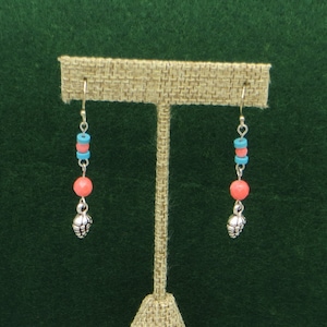 Puede incluir: Un par de pendientes colgantes con abalorios de piña de plata, cuentas de coral y turquesa.