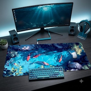 May include: A rectangular desk mat featuring a vibrant illustration of koi fish swimming in a blue pond with rocks and aquatic plants. The mat is positioned on a dark surface beneath a computer monitor, a mechanical keyboard, and a computer mouse.