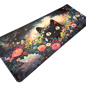 May include: A rectangular desk mat featuring a black cat with large yellow eyes peeking out from a dense garden of colorful flowers including pink, orange, and white blossoms against a dark, shadowed background with soft light.