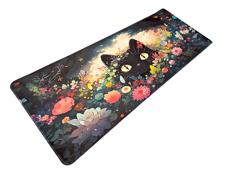 May include: A rectangular desk mat featuring a black cat with large yellow eyes peeking out from a dense garden of colorful flowers including pink, orange, and white blossoms against a dark, shadowed background with soft light.