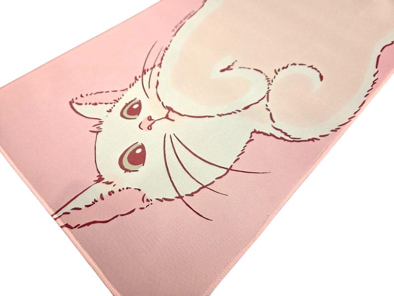 May include: A rectangular mat featuring a light pink background with a large, white, stylized cat illustration. The cat has dark pink outlines, large dark pink eyes, and long whiskers, positioned centrally on the soft-textured surface.