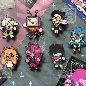 以下が含まれることがあります： Ralsei、Mike、Spamton、Berdly、Noelle、Susie、Krisなど、ゲーム「Deltarune」のキャラクターを描いた7つのエナメルピンバッジのコレクション。暗い背景の上に配置され、装飾的な白いプラス記号とテキストが添えられています。